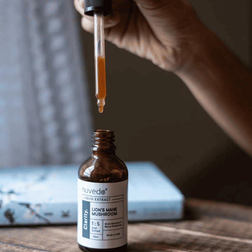 Bottle of nuveda Lion's Mane Mushroom Liquid Extract with a dropper on a wooden surface.